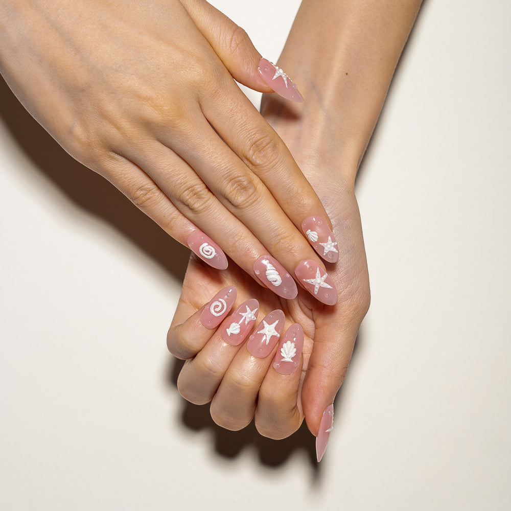 Beachy Pink Press-On Nails with Starfish & Seashell Design displayed elegantly in a bright coastal setting, highlighting the whimsical and chic nature of the manicure set.