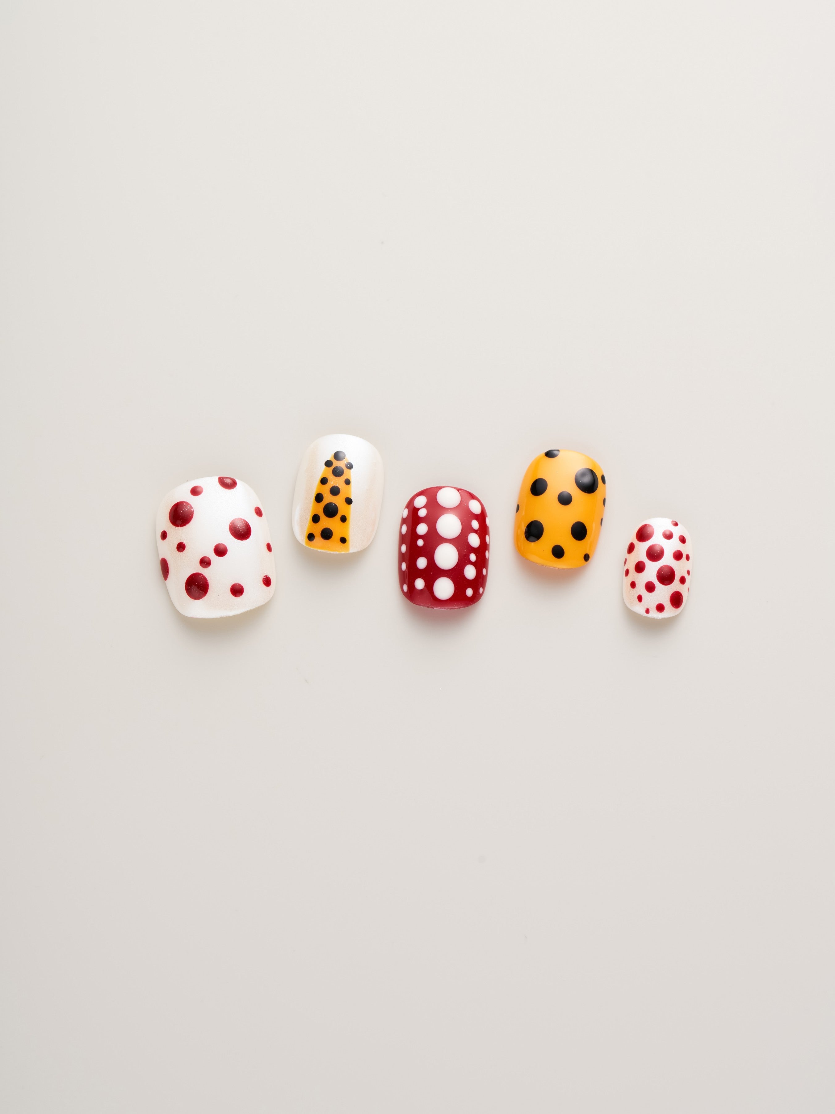 Different styles of Playful Polka Dot Squoval Press-On Nails in red, orange, black, and white polka dots, perfect for trendy nail art.