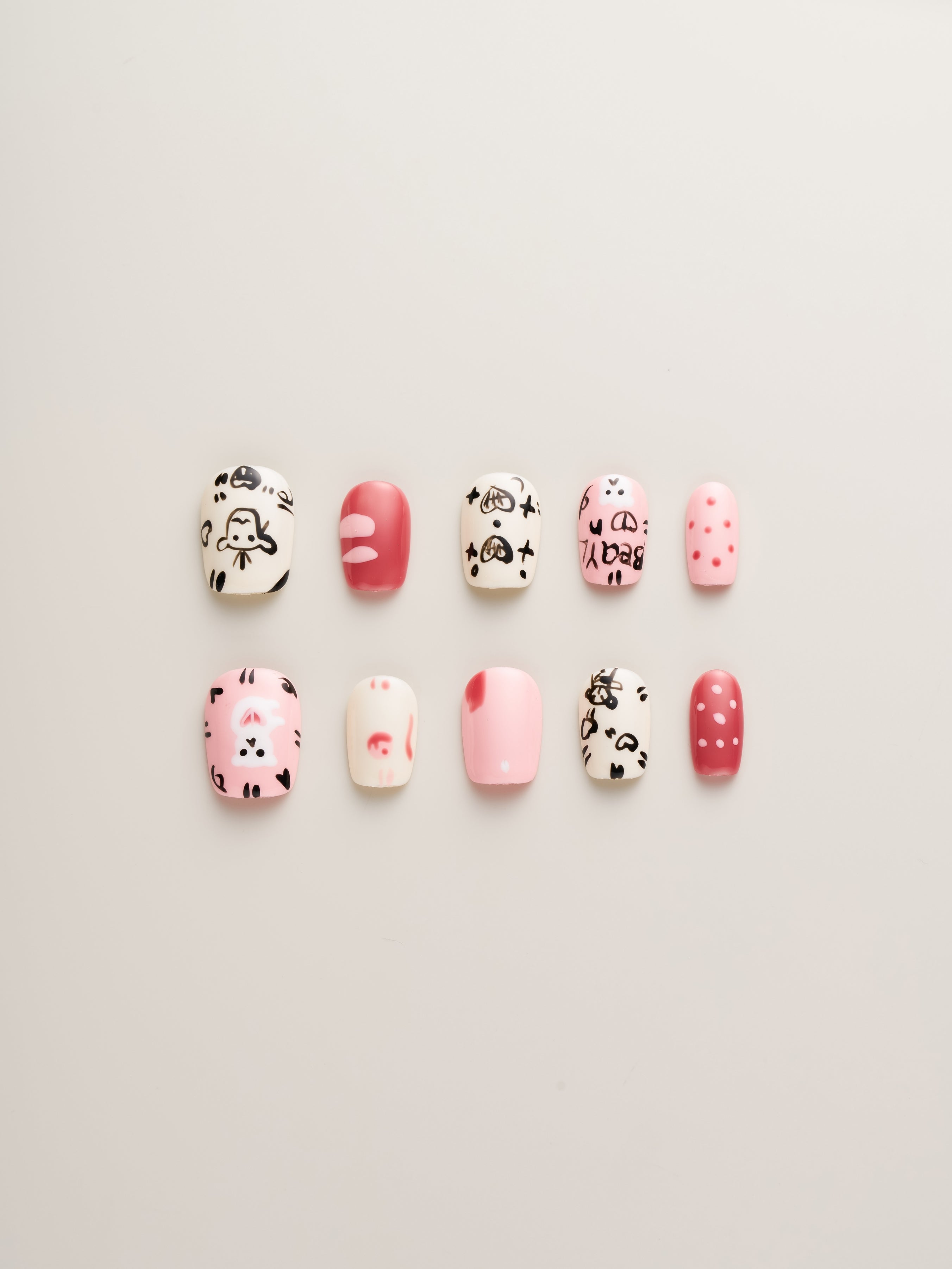 Playful Pink Cartoon Squoval Press-On Nails showcasing a vibrant mix of whimsical cartoon characters, hearts, and polka dots, perfect for expressing personality with fun nail art.