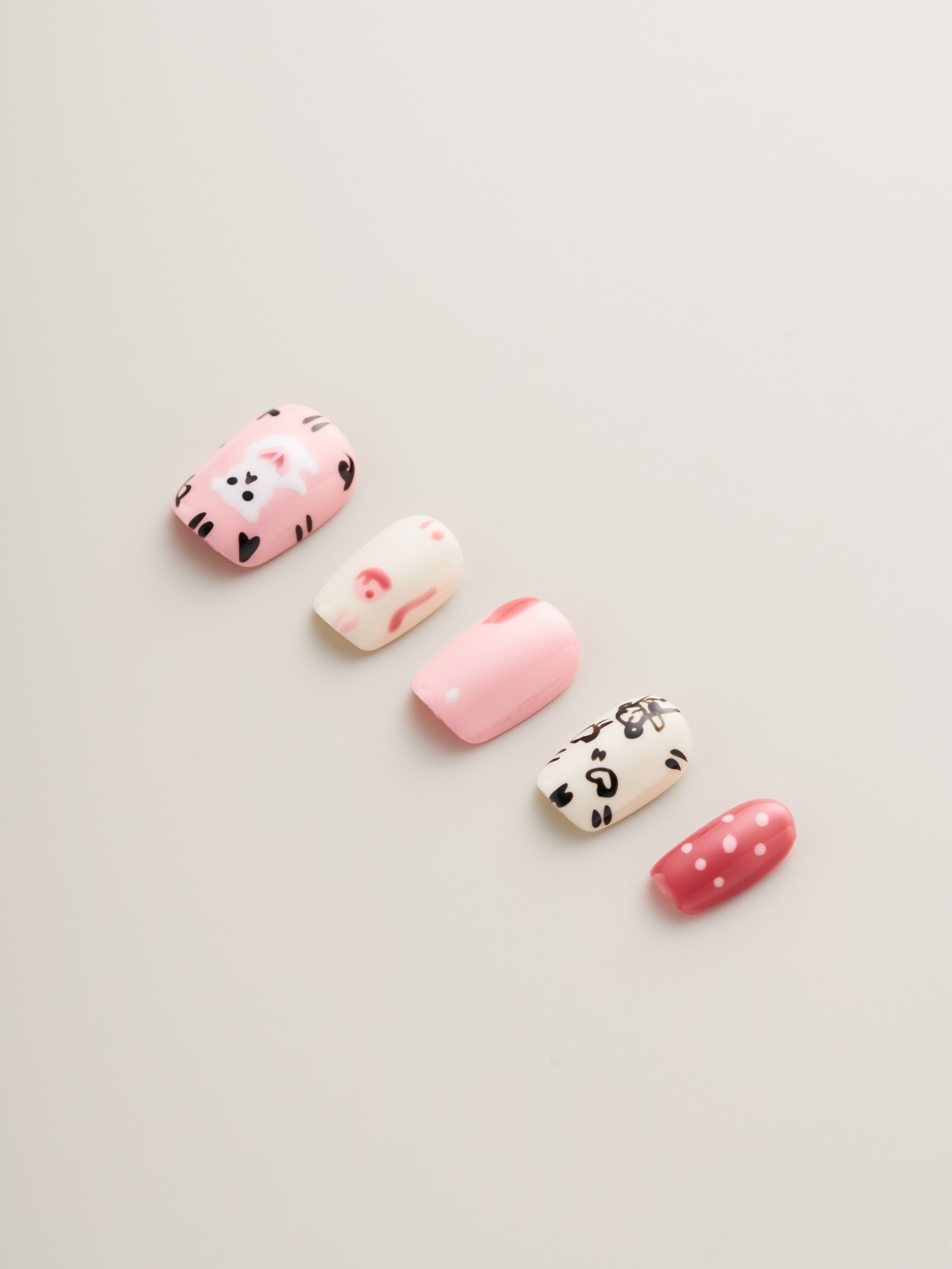 Detail shot of Playful Pink Cartoon Squoval Press-On Nails highlighting charming pink and white designs with adorable illustrations and polka dots, a must-have for trendy nail lovers.