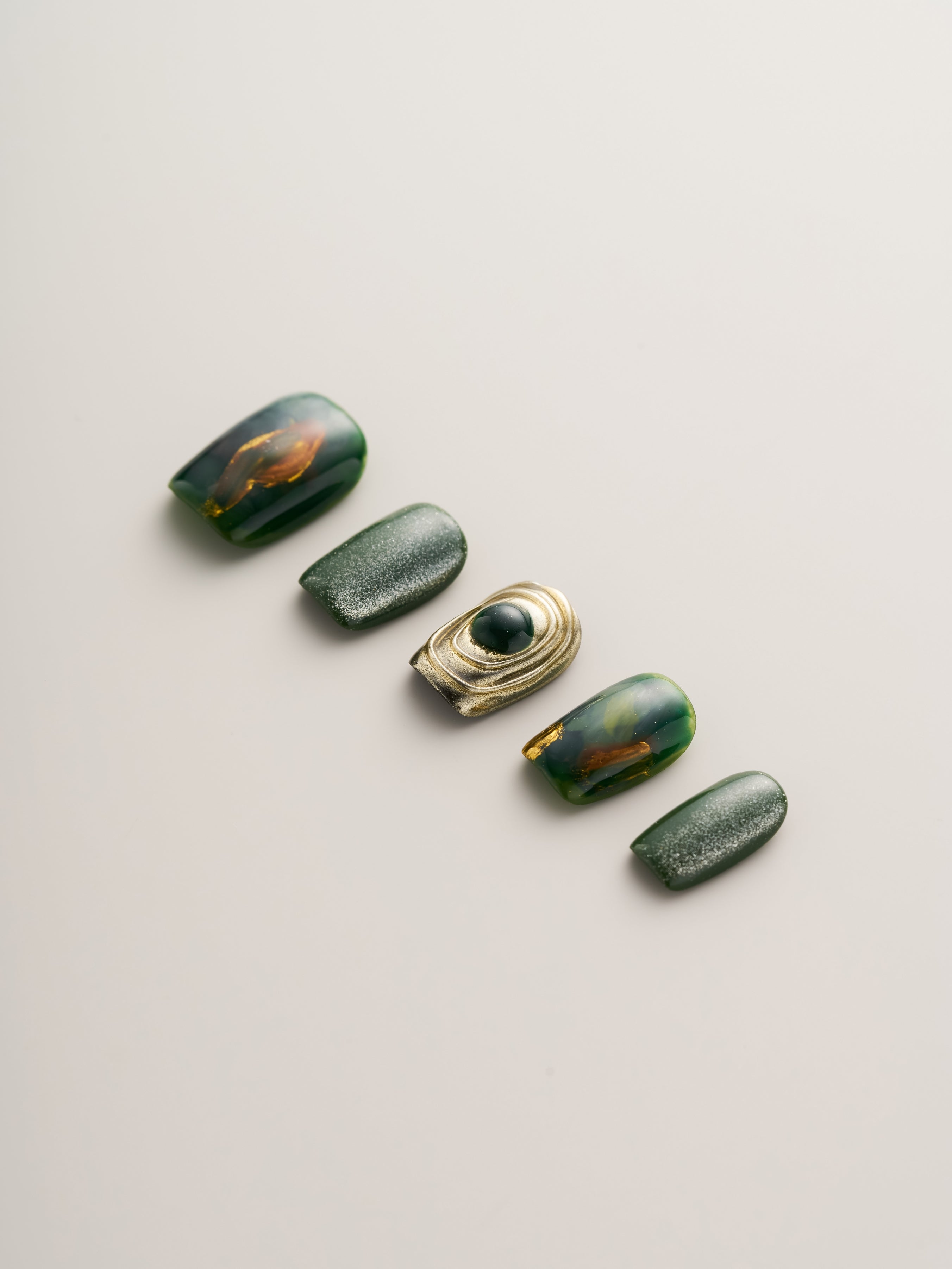 Close-up view of the Emerald Elegance Squoval Press-On Nails displaying luxurious emerald tones and intricate design details, ideal for a bold fashion statement.
