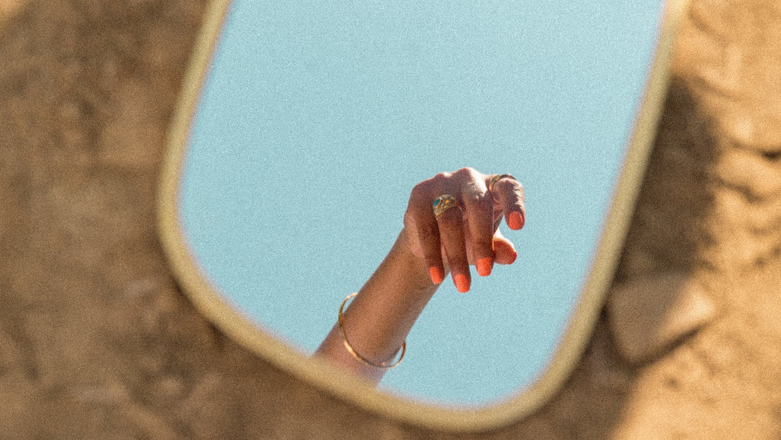 Close-up of stylish hands showcasing the 2025 Summer Collection by Nailè, featuring iridescent blue press-on nails with ocean-inspired designs like seashells and glitter, perfect for a coastal dreamy aesthetic.