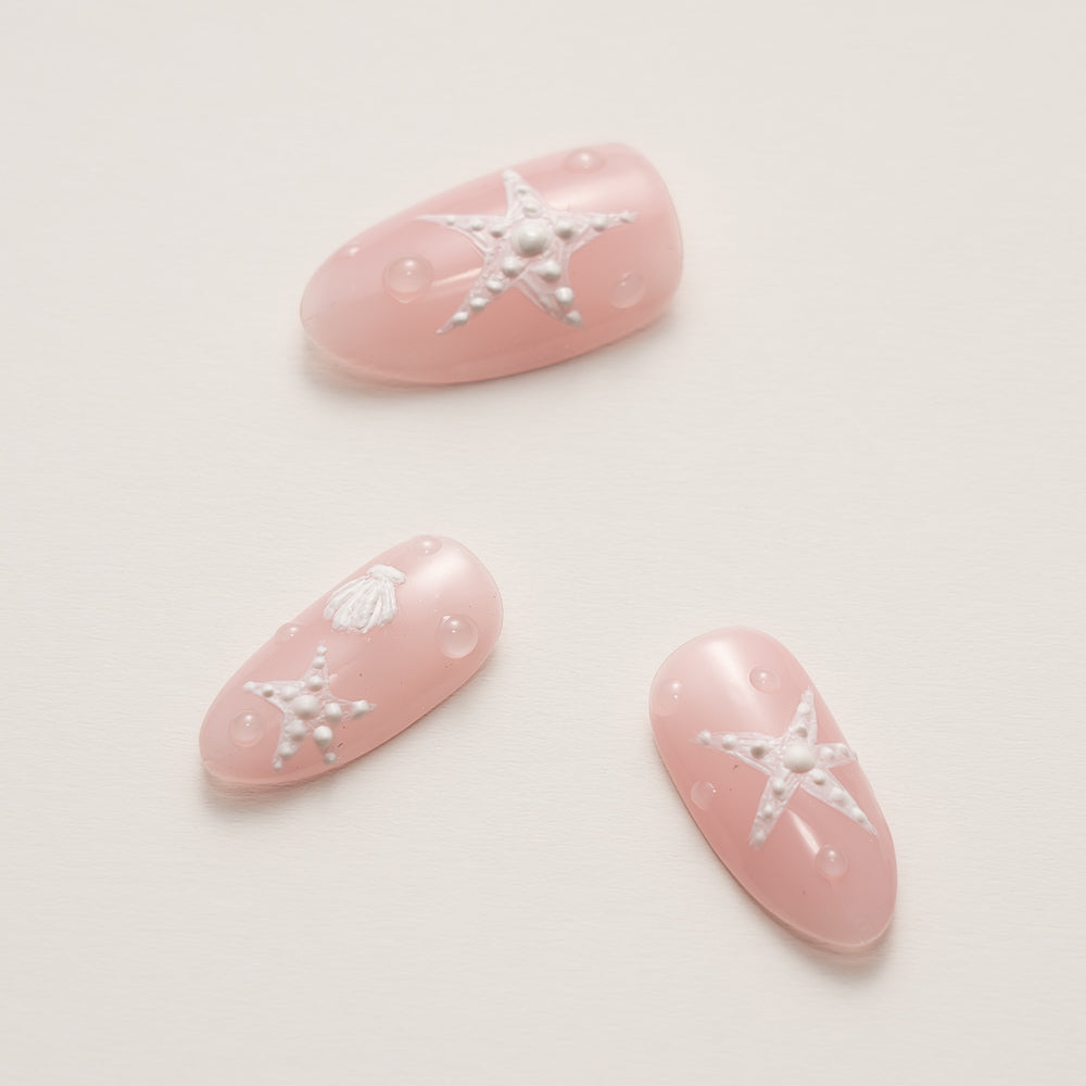 Close-up of Beachy Pink Press-On Nails with Starfish & Seashell Design revealing delicate embossed details and the soft blush aesthetic of the coastal manicure set.