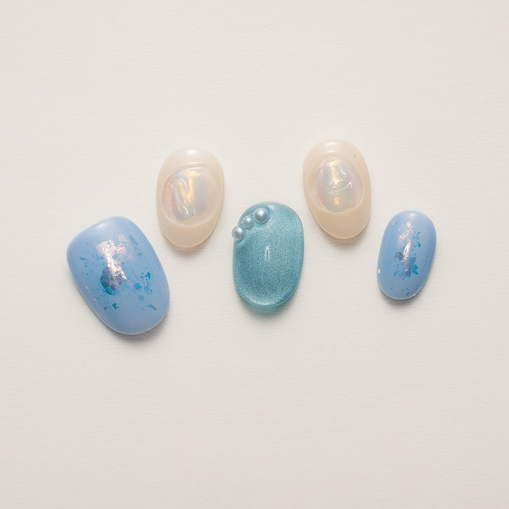 Close-up of Iridescent Mermaid Glow Press-On Nails featuring shimmering aquamarine hues and embedded pearls, perfect for an underwater fantasy look.