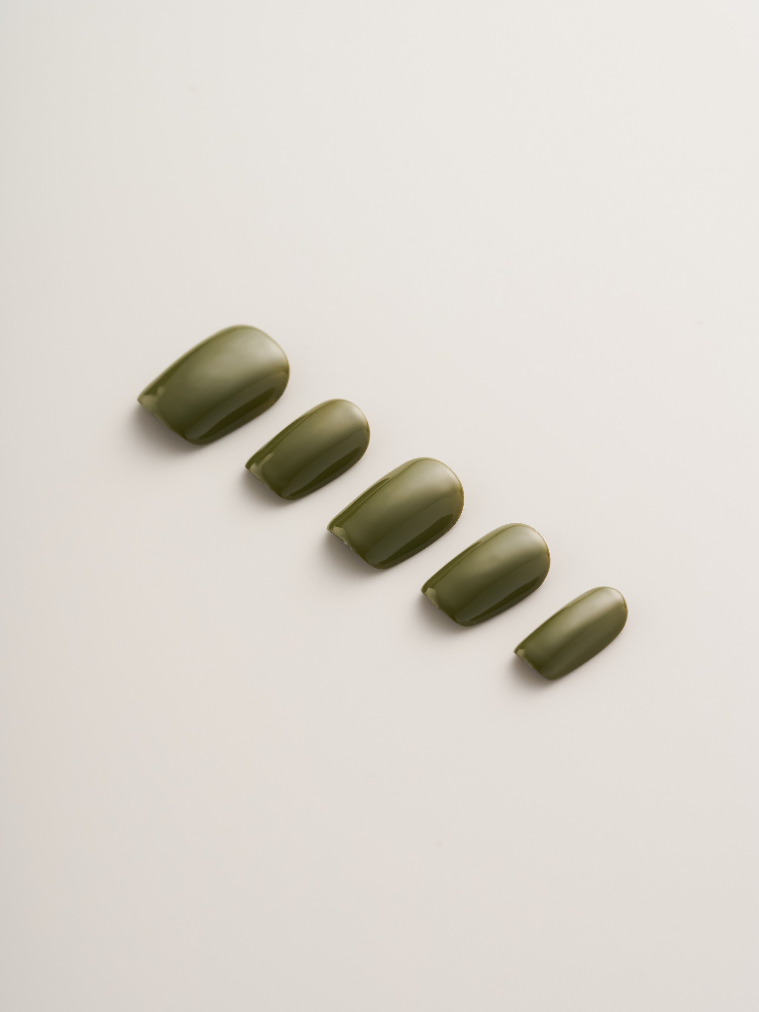 Minimalist Olive Green Squoval Press-On Nails arranged in a line showcasing different sizes for easy selection.