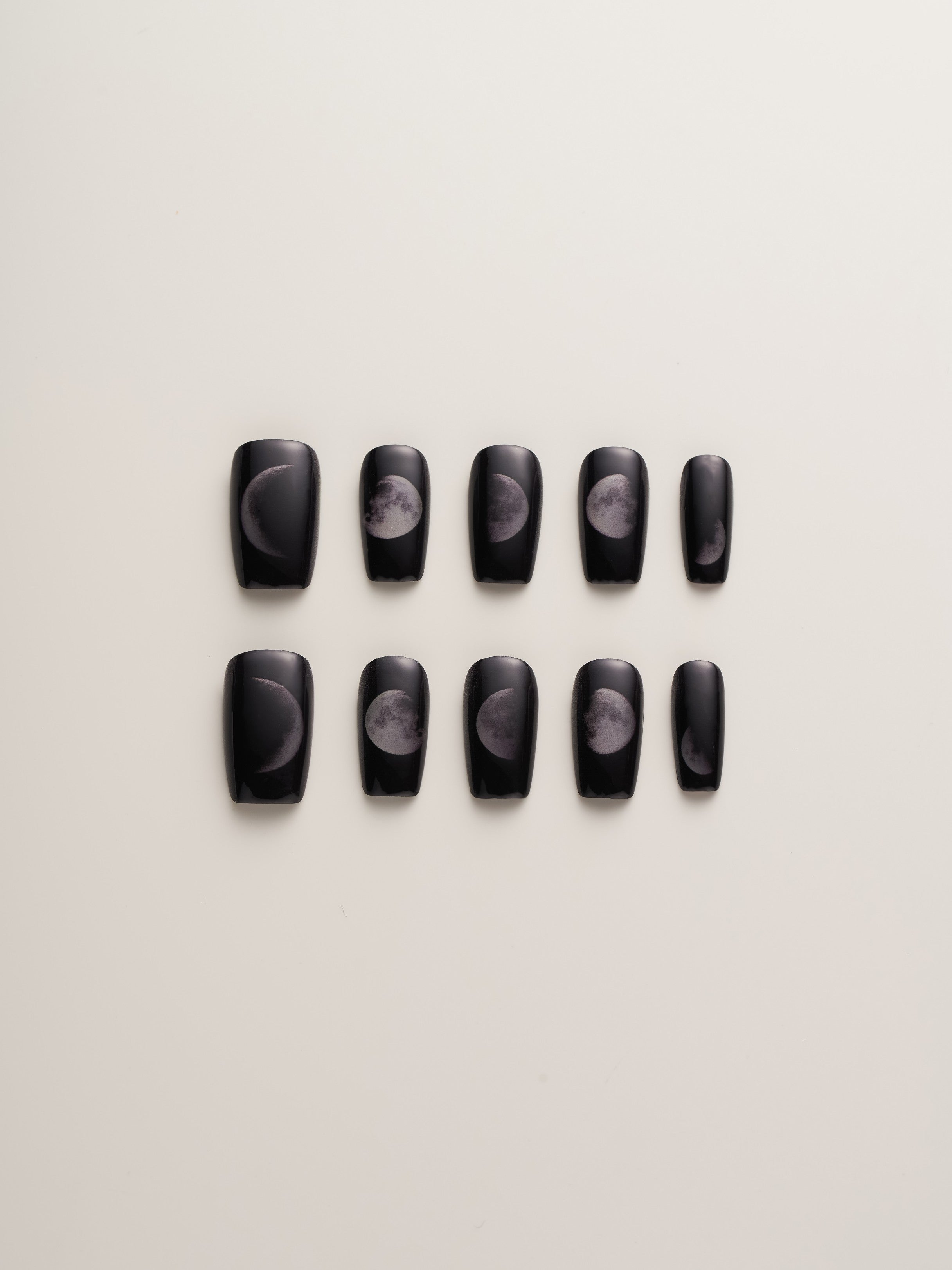 Mystical Moon Phases Squoval Press-On Nails displayed in a set, showcasing intricate moon phase designs on a sleek black base, ideal for astrology enthusiasts.