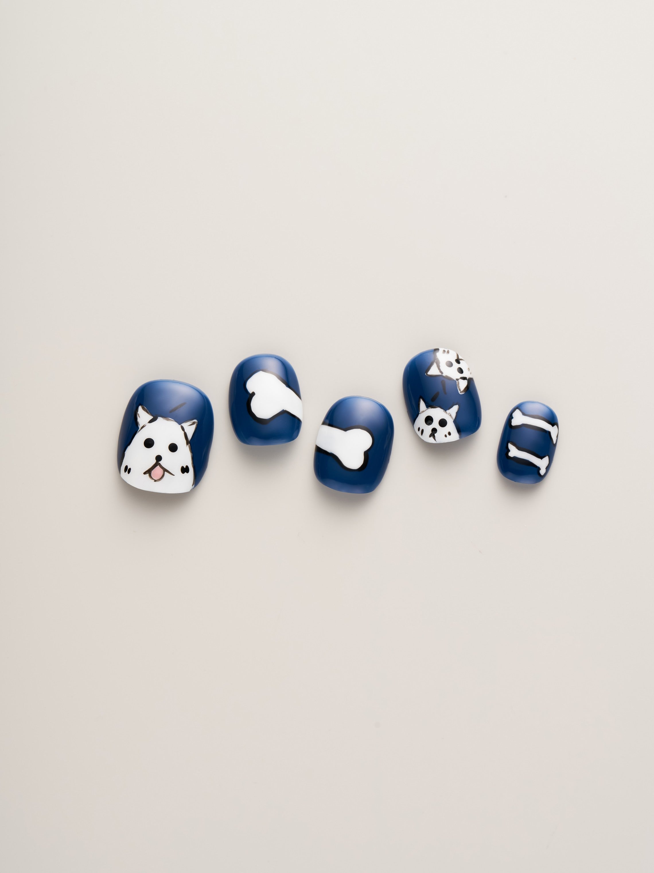 Close-up view of Bold Blue Dog Lover’s Squoval Press-On Nails with charming dog-themed designs, showcasing playful dog faces and bones.