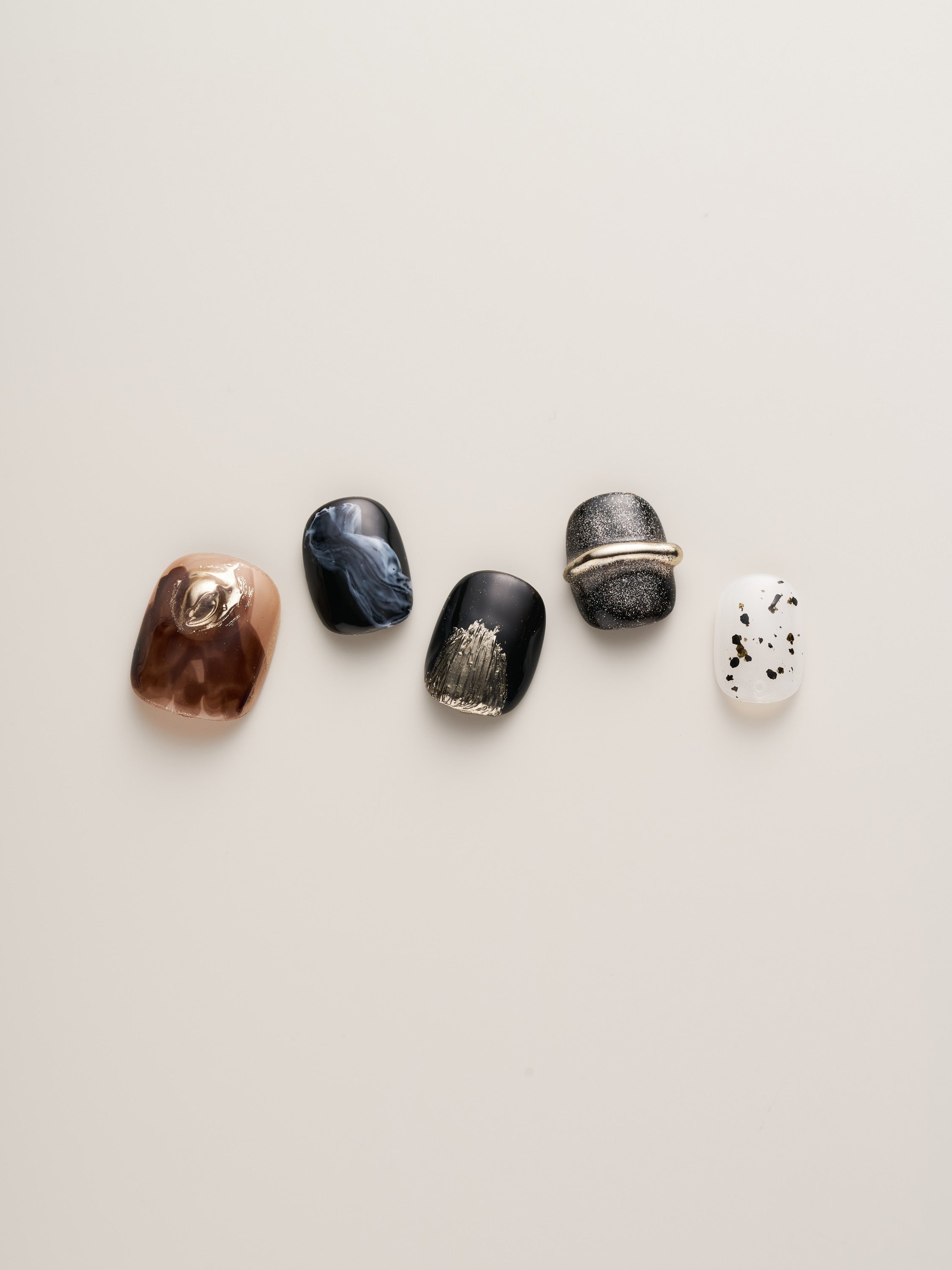 Close-up view of Luxury Metallic Accent Squoval Press-On Nails showing intricate designs with black, marble, and speckled patterns, all enhanced by chic metallic elements.