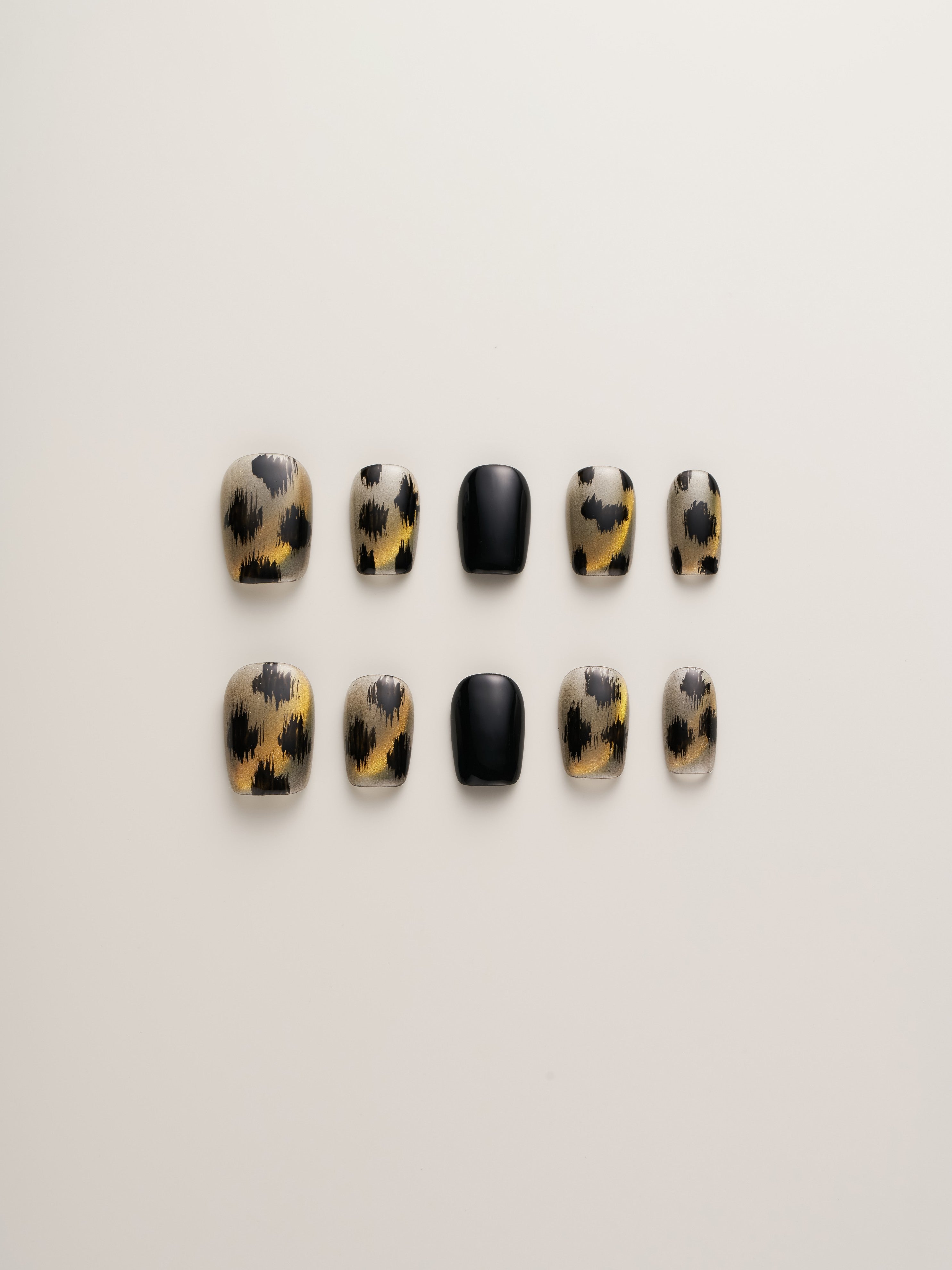 Leopard Print Glam Squoval Press-On Nails arranged neatly in rows showcasing bold leopard patterns and glossy black finishes.