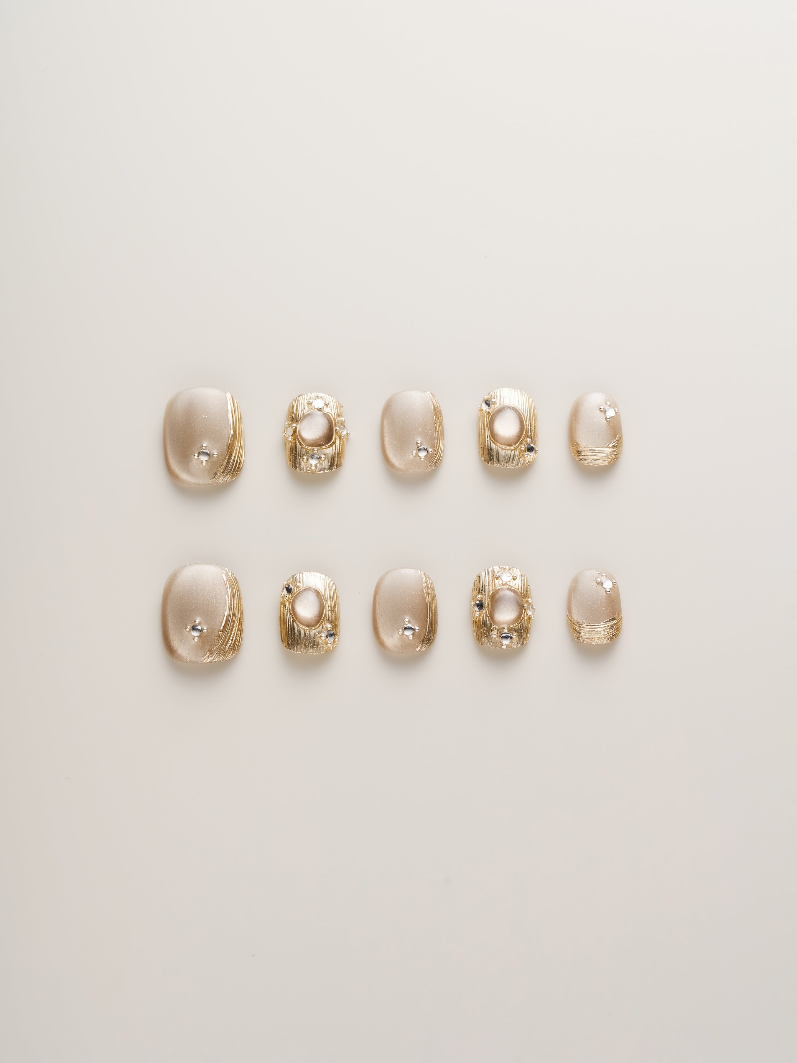 Golden Luxe Metalli Squoval Press-On Nails displayed in a variety of sizes with champagne gold finish and textured embellishments.