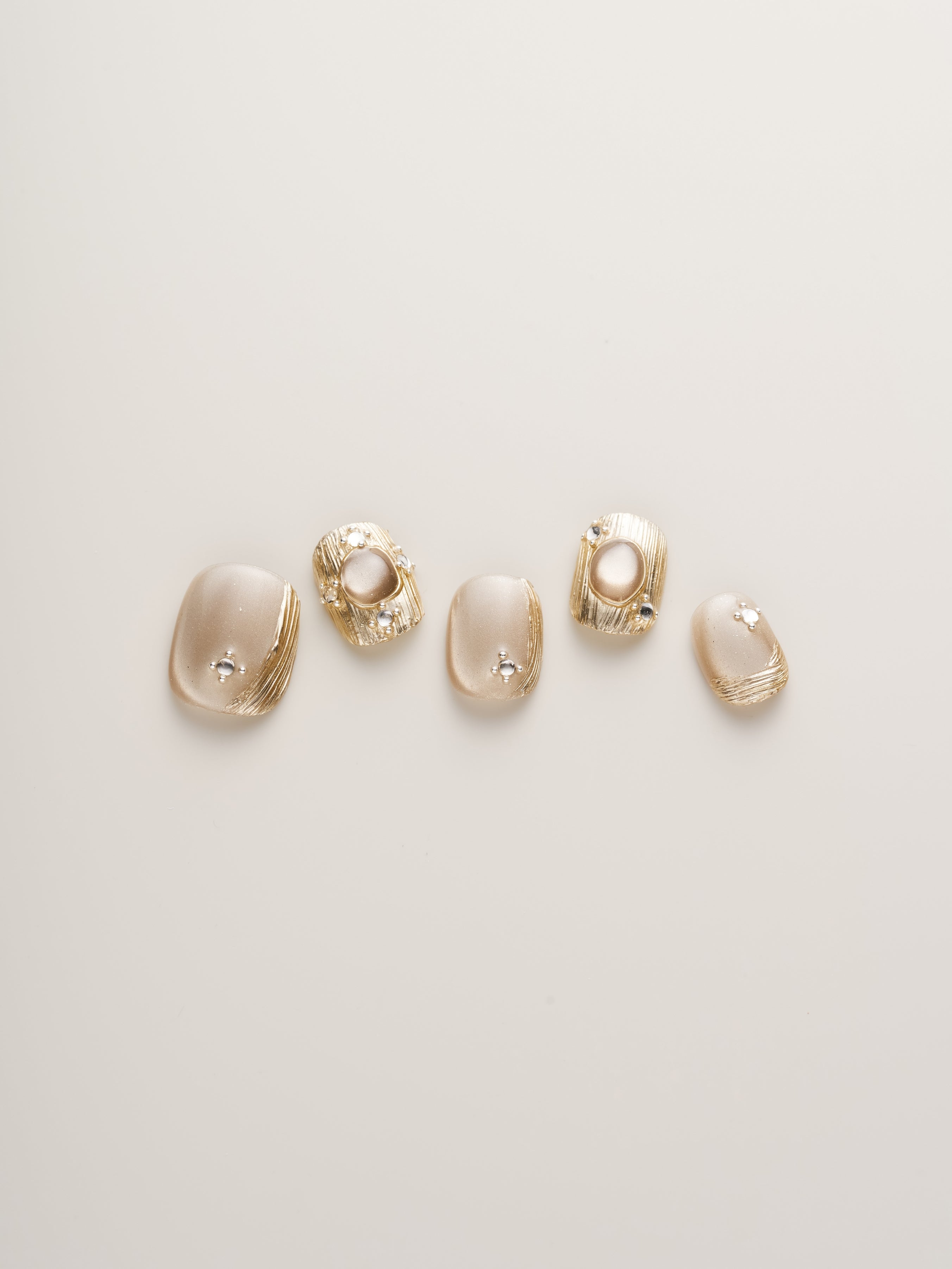 Golden Luxe Metalli Squoval Press-On Nails featured in a stylish layout showing five uniquely designed nails with a luxurious gold tone.