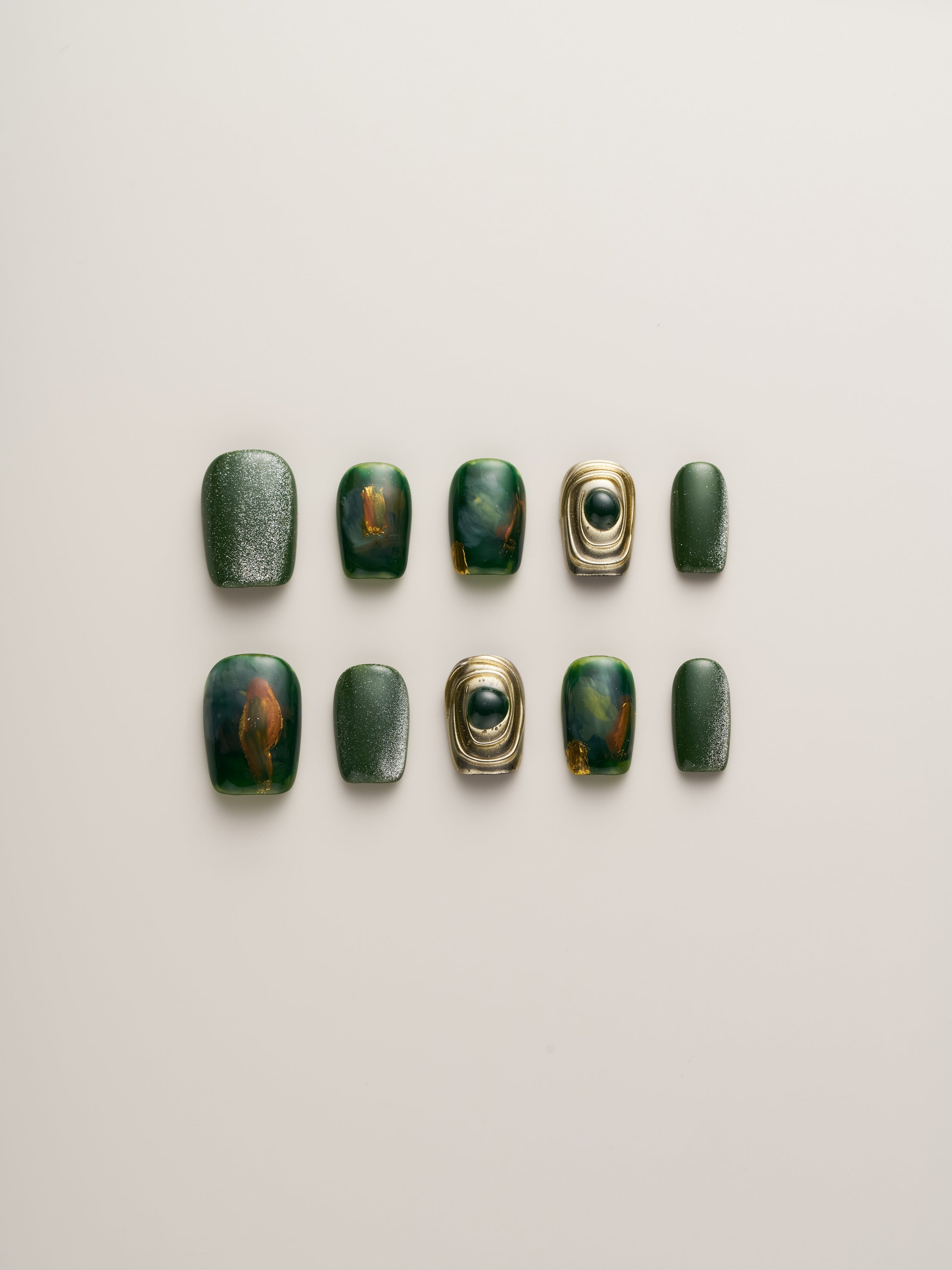 Emerald Elegance Squoval Press-On Nails set showcasing a variety of emerald green shades, including marbled effects and metallic accents, ideal for a chic and stylish manicure.