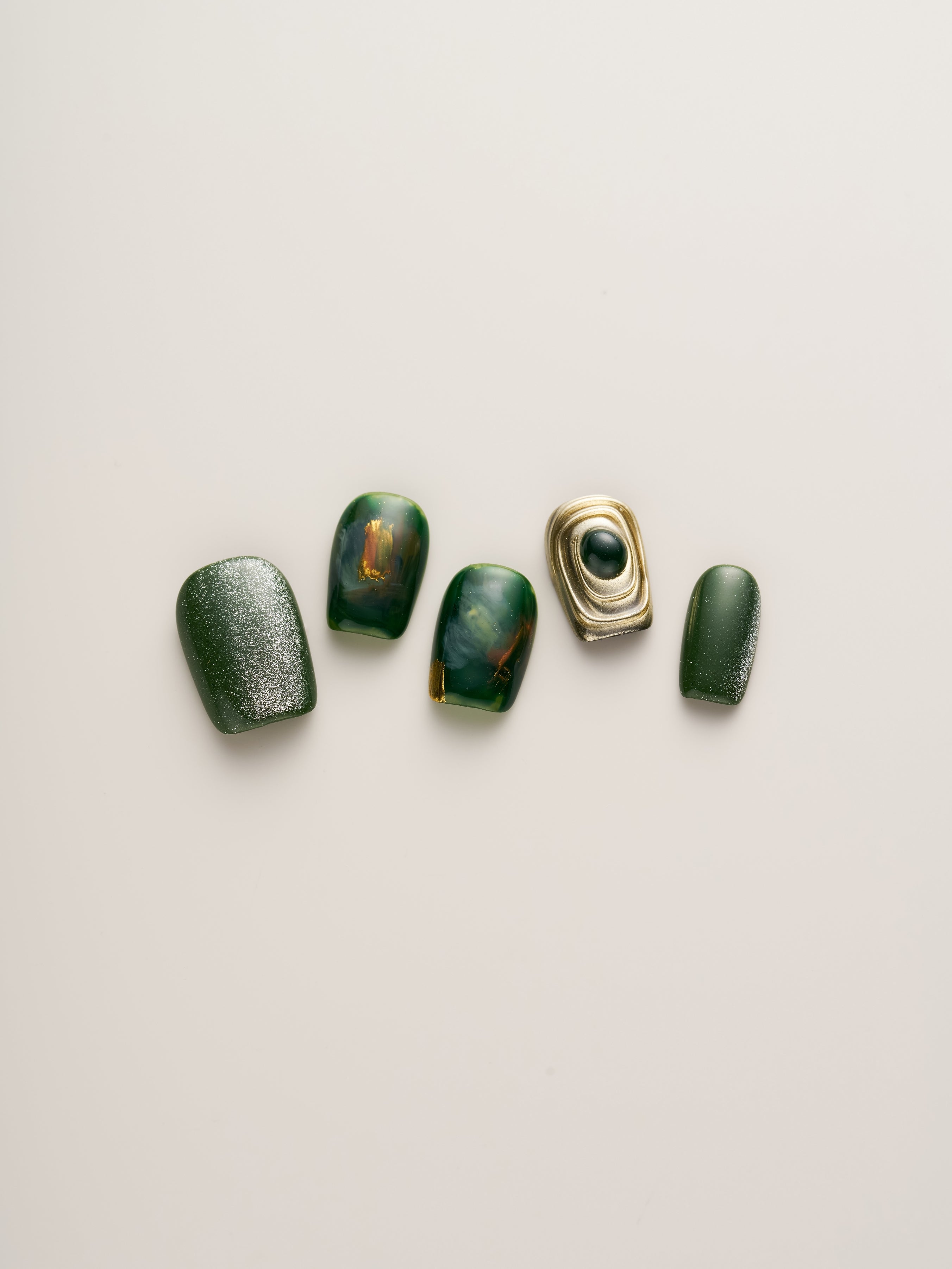 Emerald Elegance Squoval Press-On Nails arranged elegantly, highlighting different designs with glossy finishes and unique textures, perfect for easy nail styling.