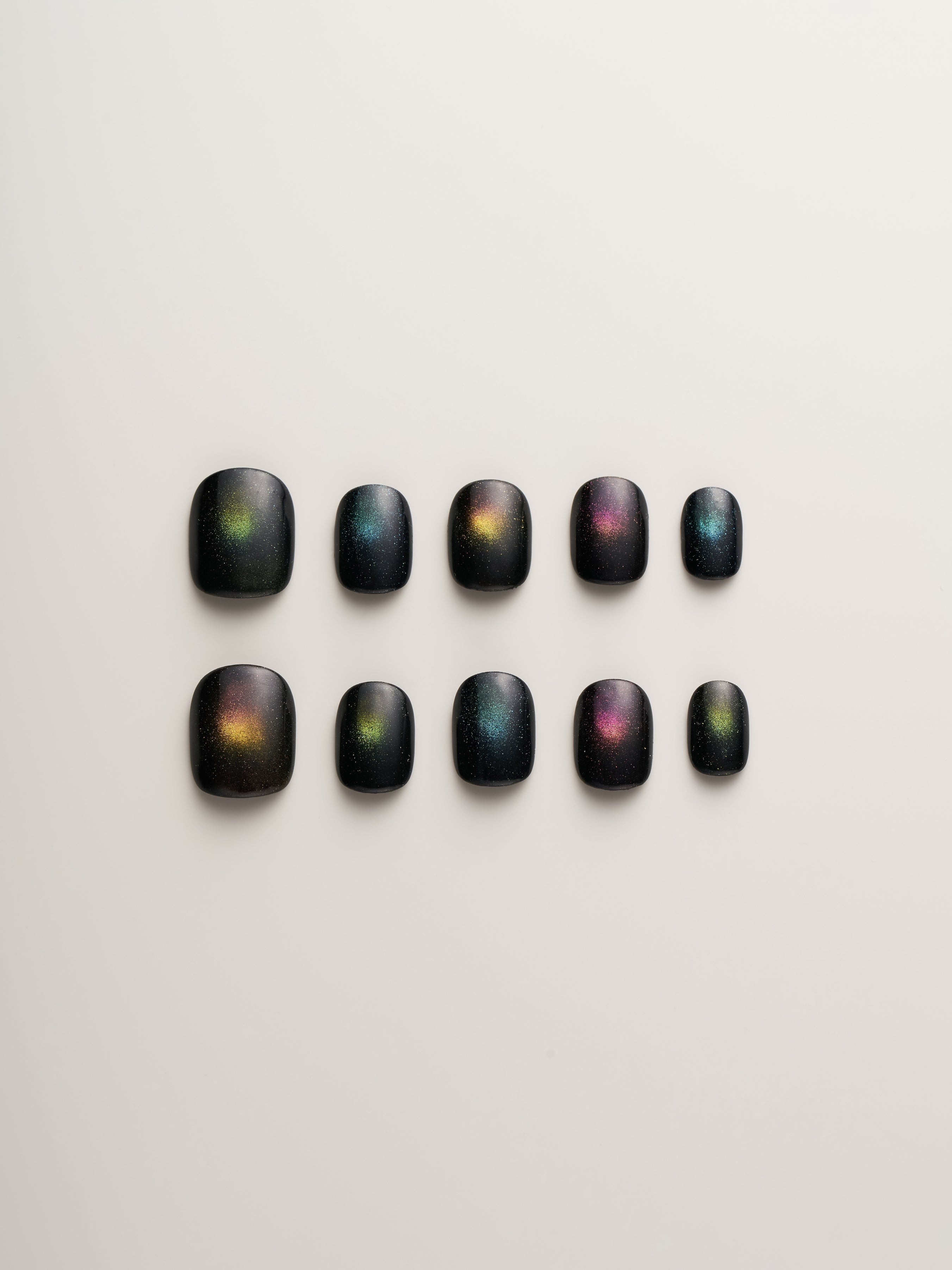Cosmic Glow Square Press-On Nails set featuring a variety of black nails embellished with holographic accents, perfect for a bold and unique look.