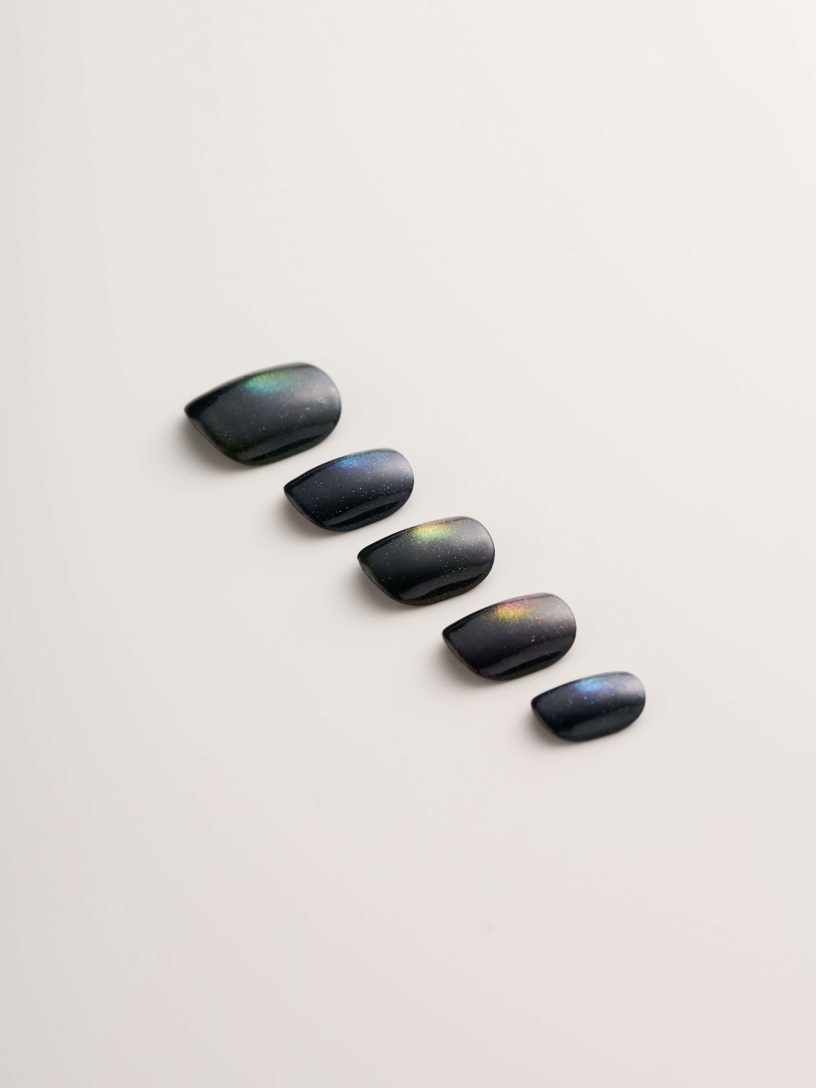Close-up of Cosmic Glow Square Press-On Nails showing five black nails with stunning holographic shimmer, ideal for effortless glam.