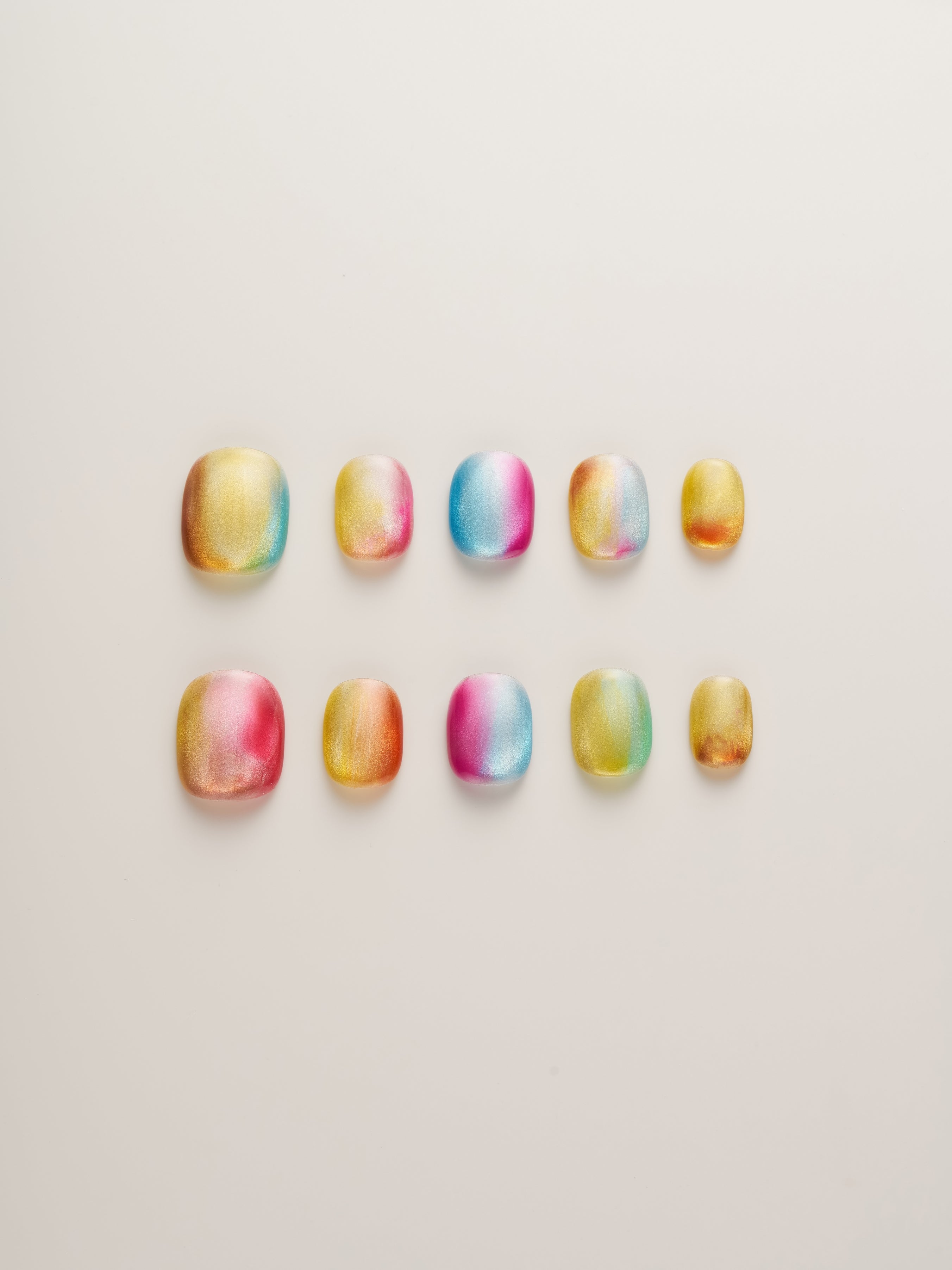 Radiant Sunset Glow Press-On Nails showcasing a vibrant array of colors with metallic finishes inspired by tropical sunsets. Colors include golden yellow, fiery red, cool blue, and soft pink arranged in an eye-catching design.
