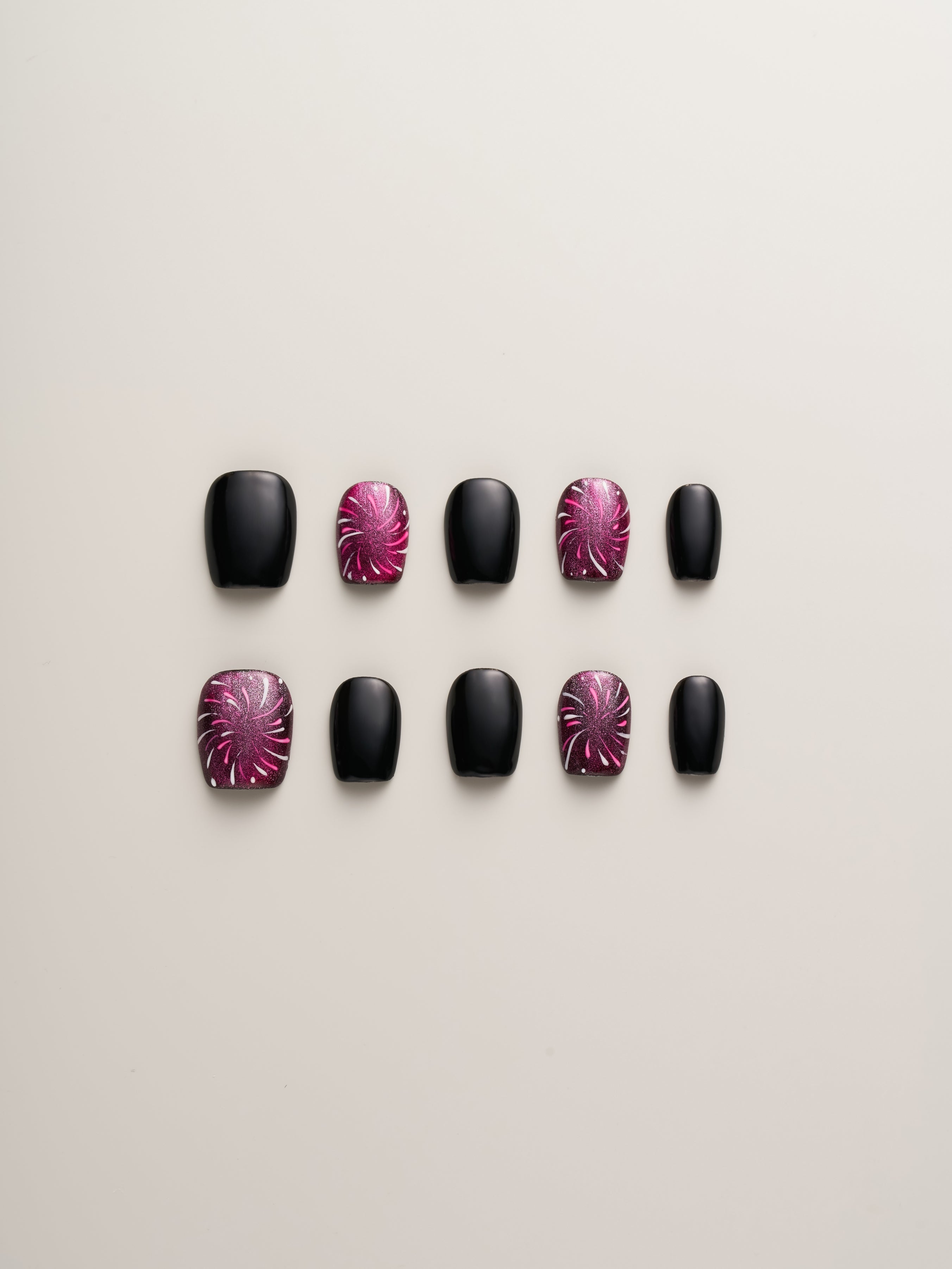 Midnight Spark Press-On Nails by Nailè, showcasing a stylish arrangement with a sleek black base and dazzling pink firework-like accents.