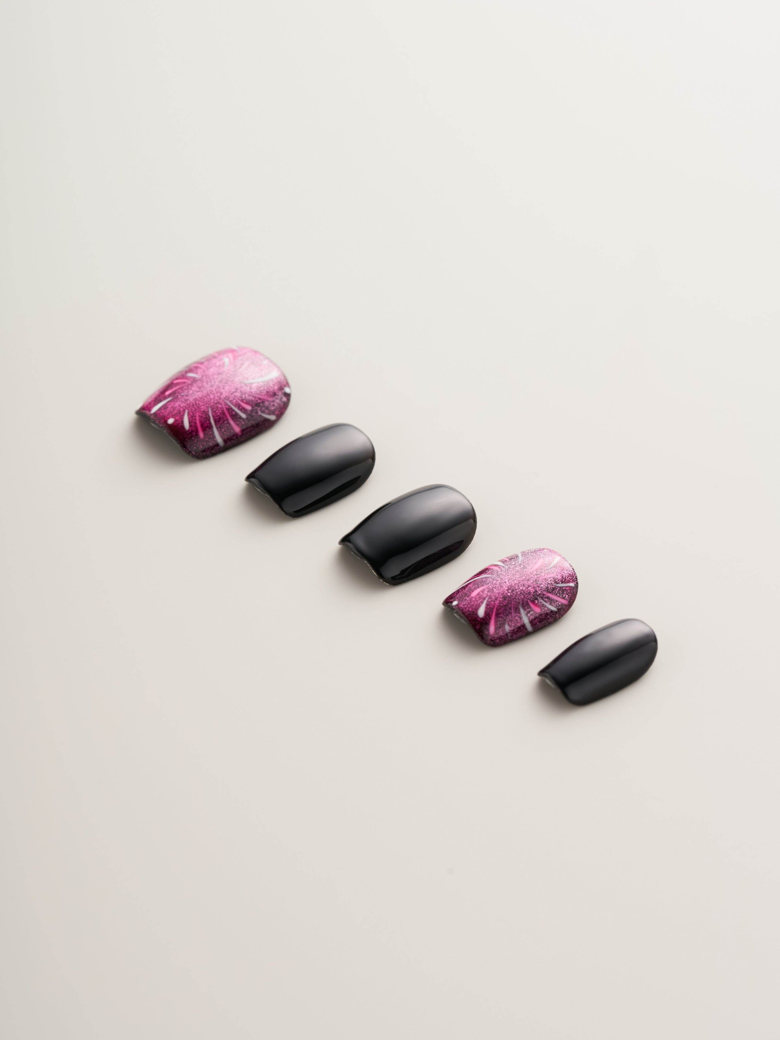 Midnight Spark Press-On Nails from Nailè, featuring a close-up of black nails with vibrant pink shimmer and dynamic designs, perfect for a bold manicure.