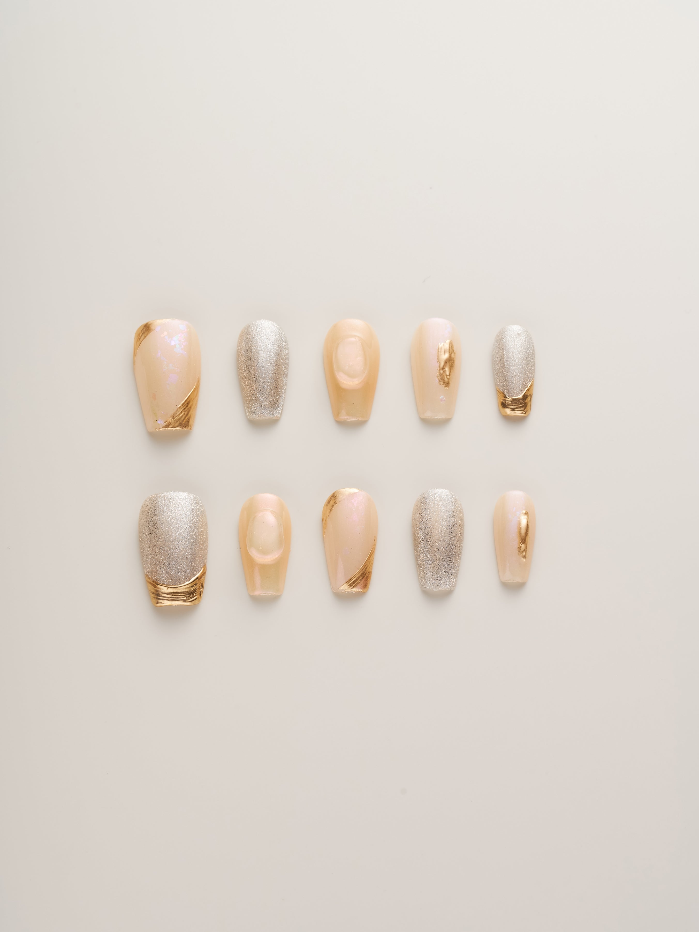 Luxe Golden Glow Press-On Nails arranged in a stylish row, showcasing a mix of soft champagne, shimmering silver, and radiant gold accents, perfect for elegant nail art.