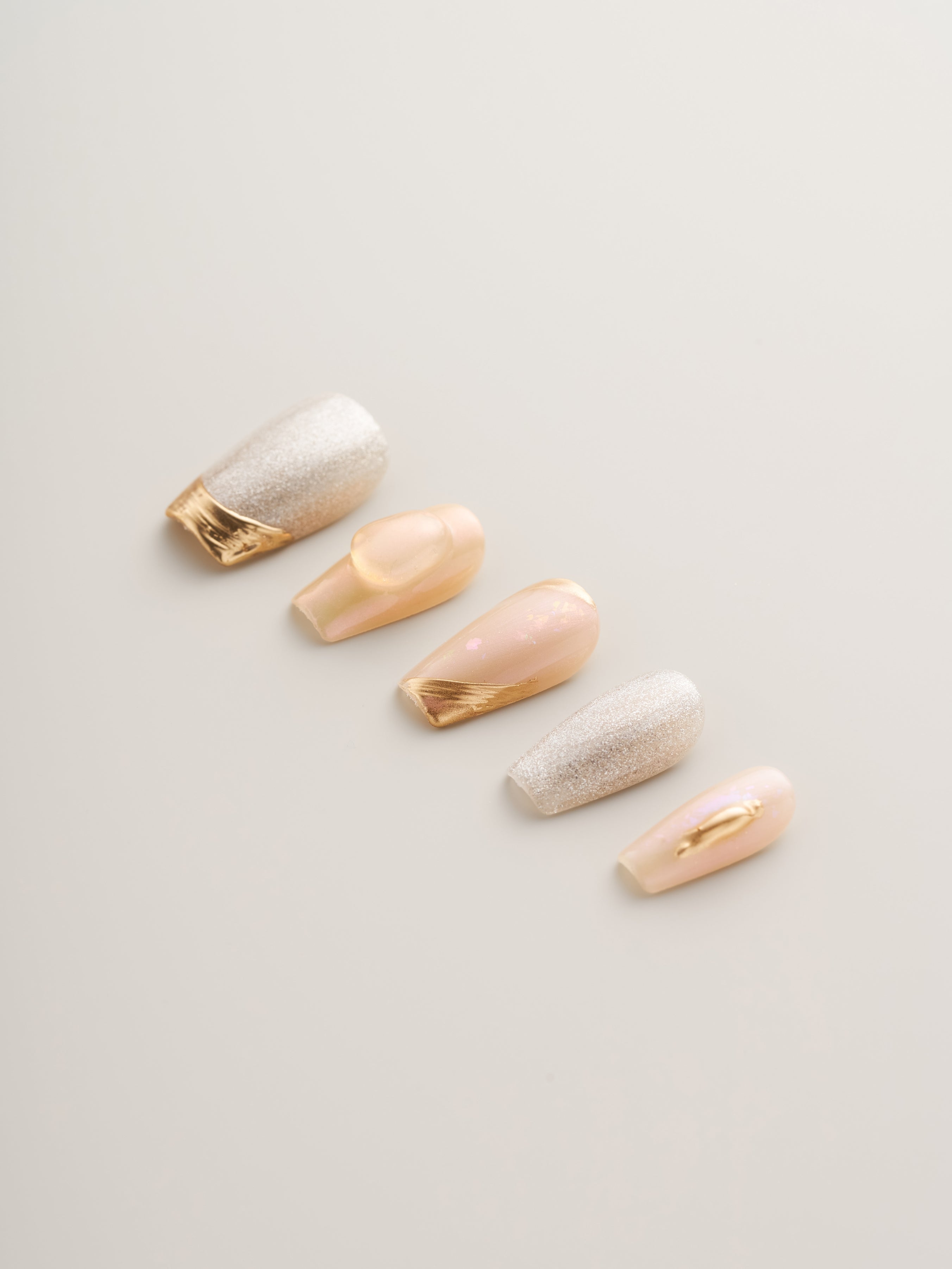 Close-up view of Luxe Golden Glow Press-On Nails with metallic accents, featuring shades of champagne and silver, ideal for adding a touch of glamour to your manicure.