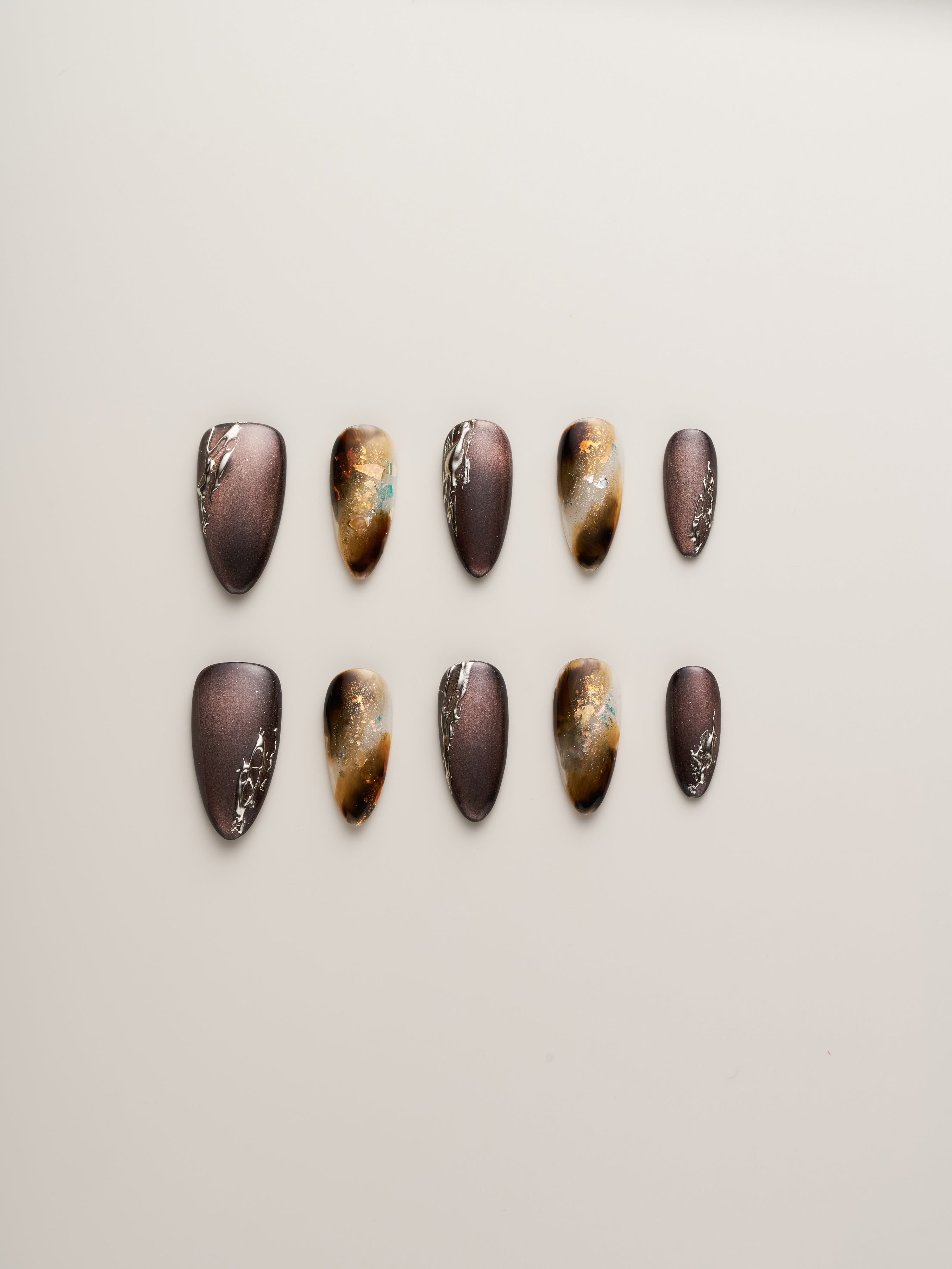 Stylish Enchanted Garden Press-On Nails by Nailè arranged in a beautiful pattern showcasing earthy tones and elegant gold accents.