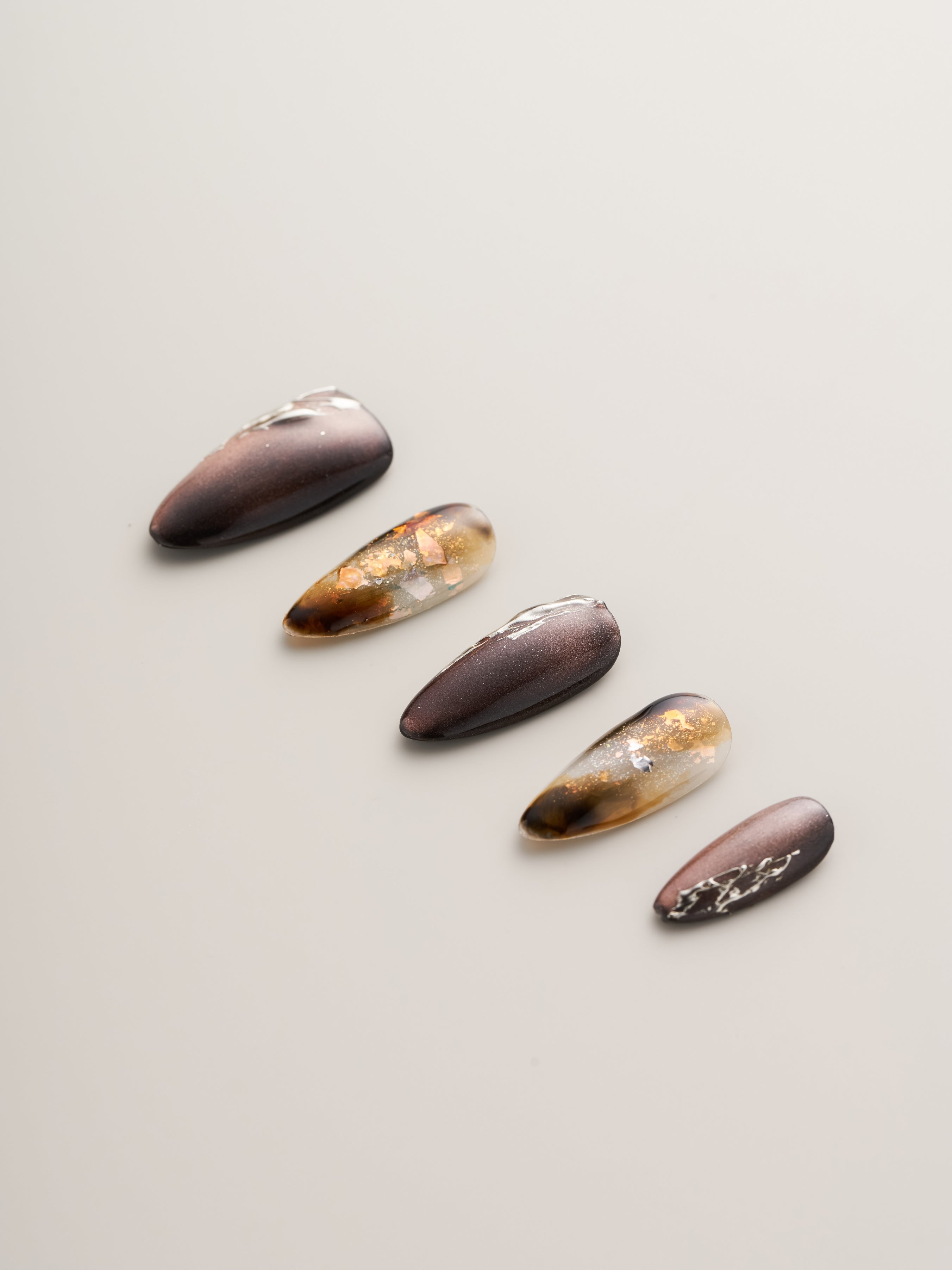 Close-up view of Enchanted Garden Press-On Nails featuring a mix of dark and shimmery colors with intricate designs, perfect for a magical look.