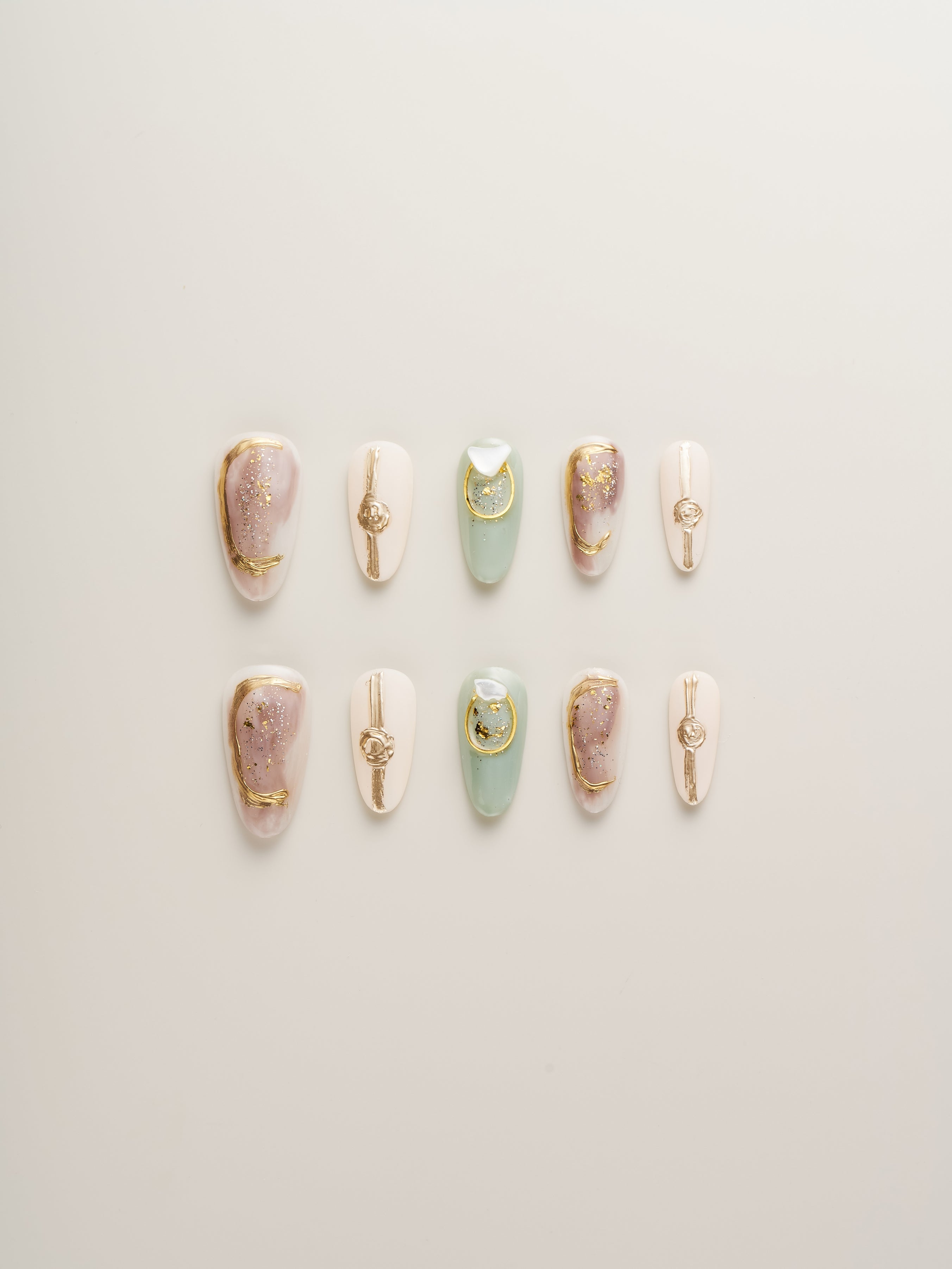 Set of Celestial Harmony Press-On Nails featuring shades of lilac, mint green, and nude with gold accents, elegantly arranged on a light background.
