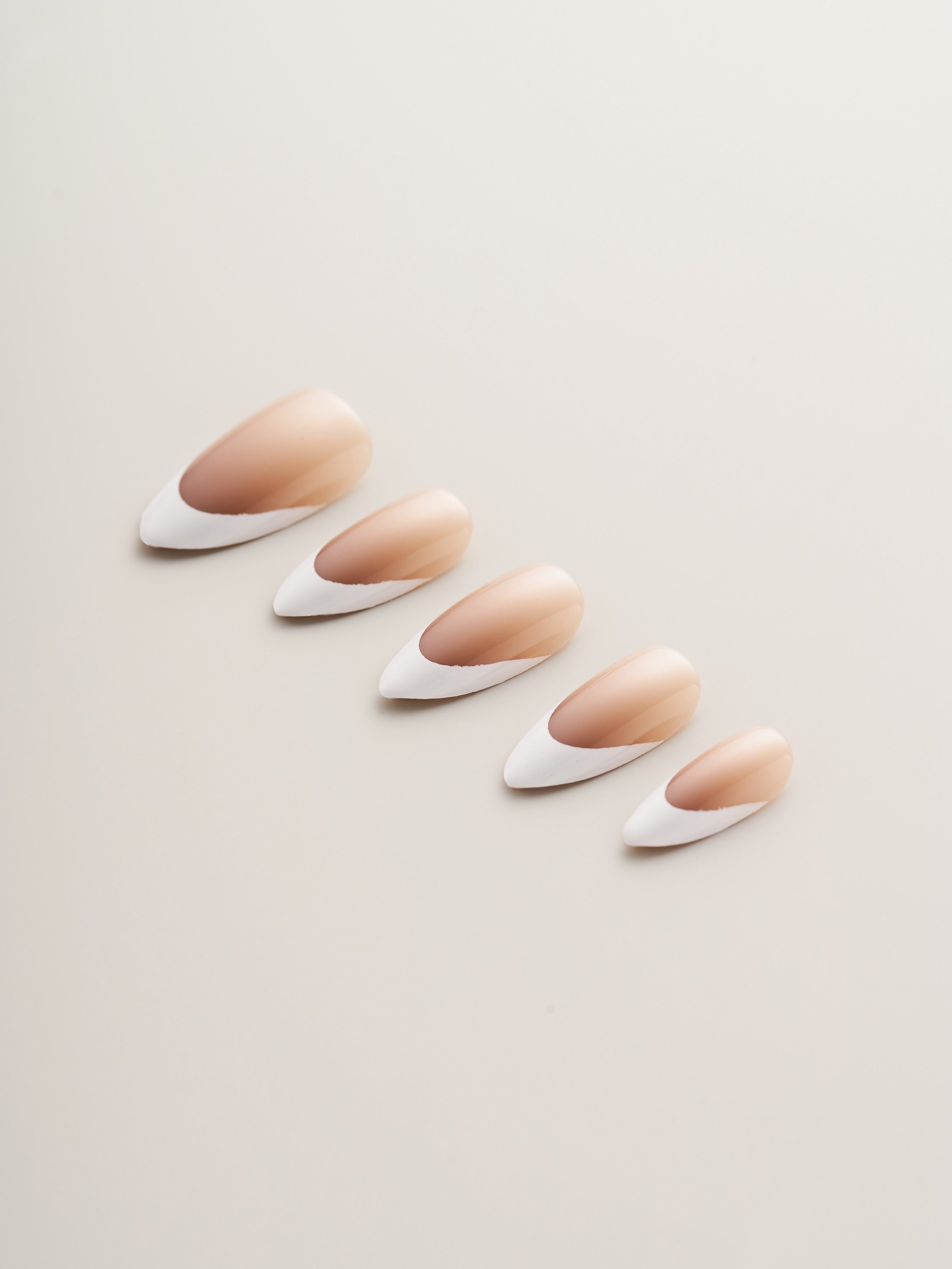 A close-up view of Classic Nude and White French Tip Almond Press-On Nails showcasing their elegant almond shape and glossy finish.