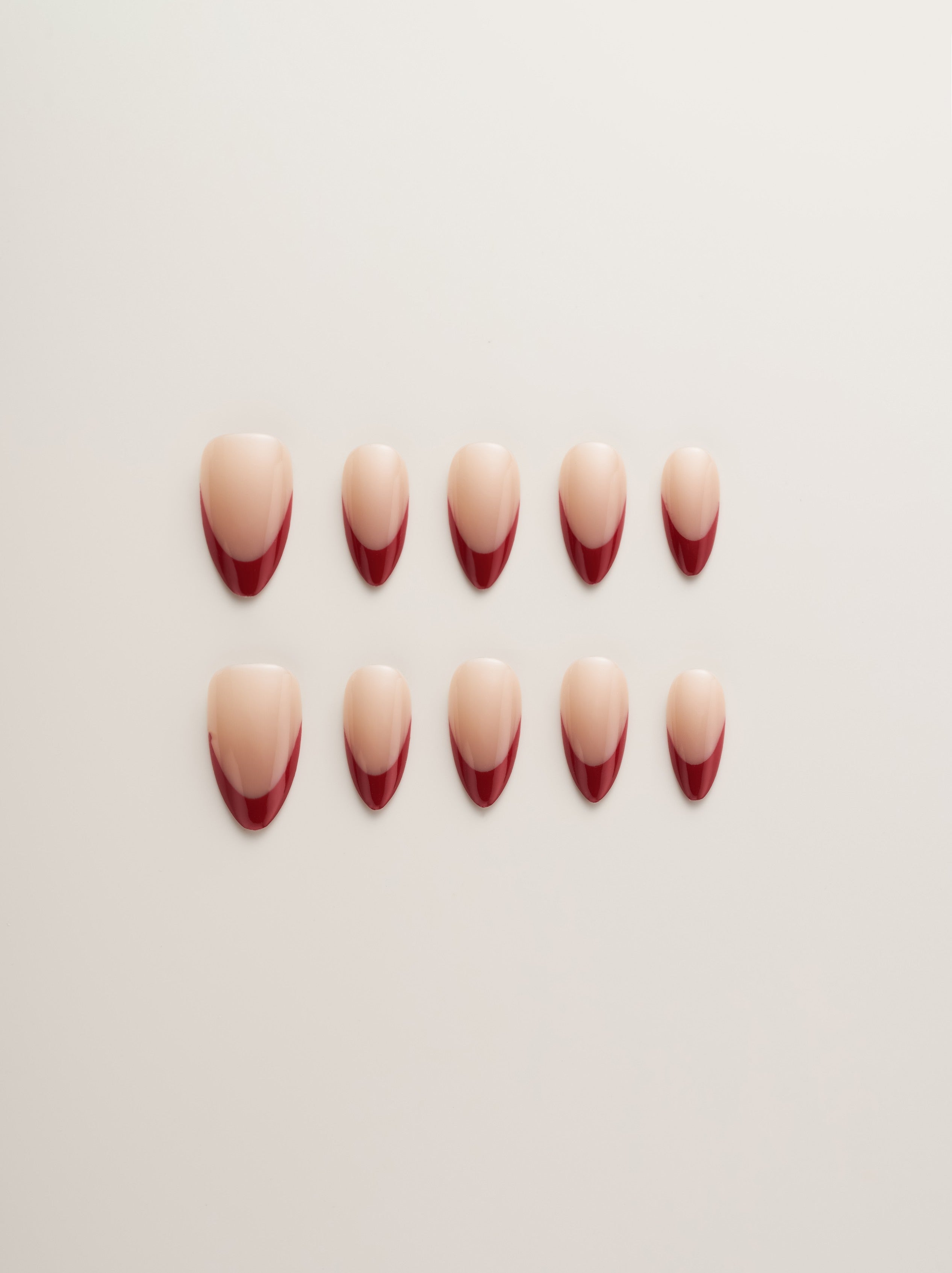Chic Red French Tip Almond Press-On Nails displayed in multiple sizes on a light background, showcasing the elegant milky white base with vibrant red tips.